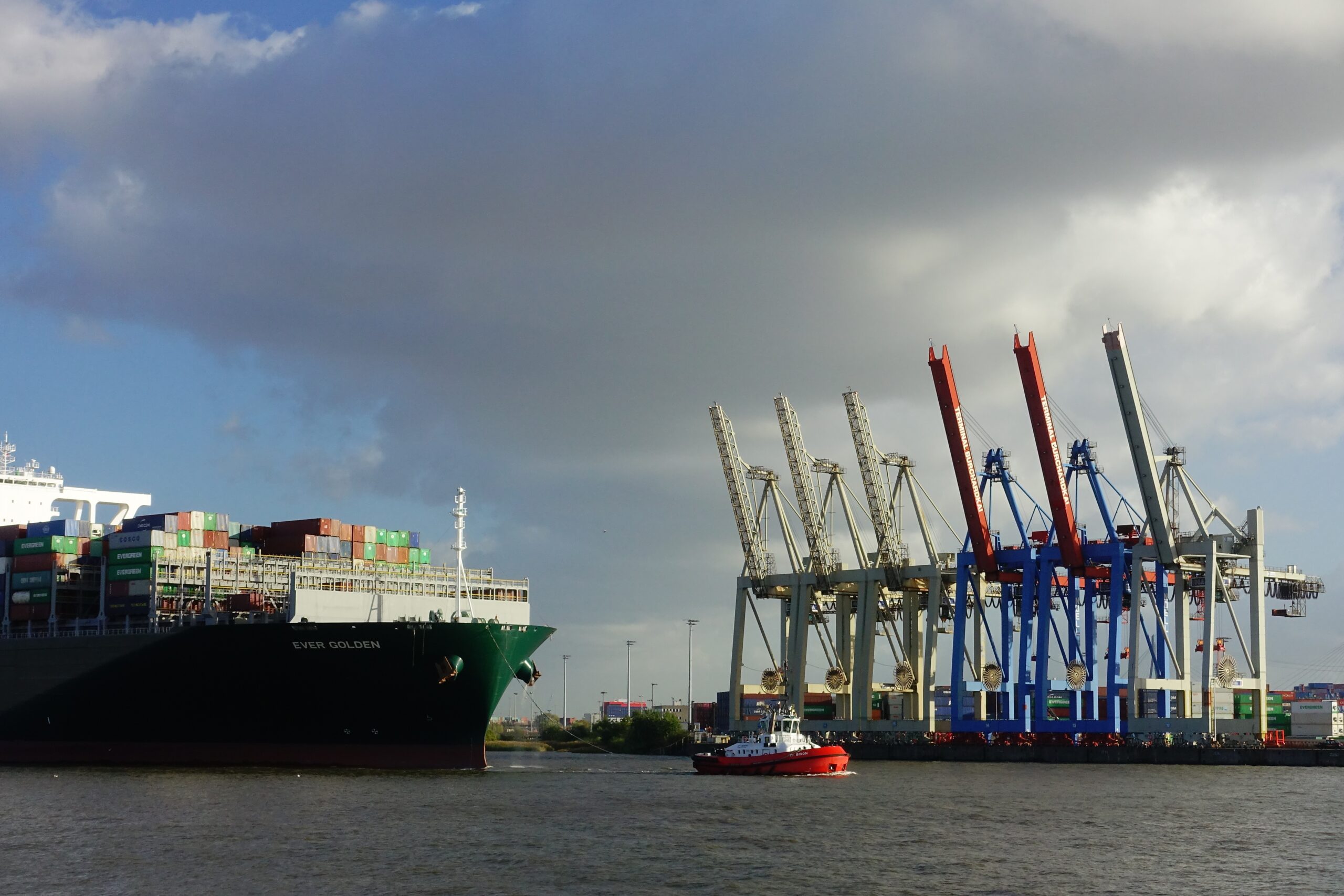big containership let by a tug boat in hamburg harbor